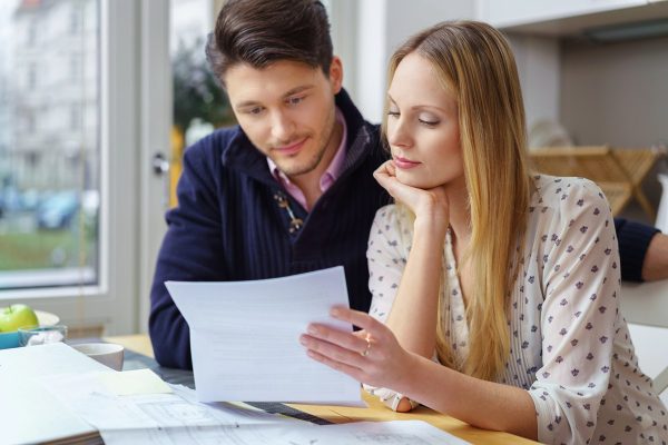Young couple at table looking at document or finances