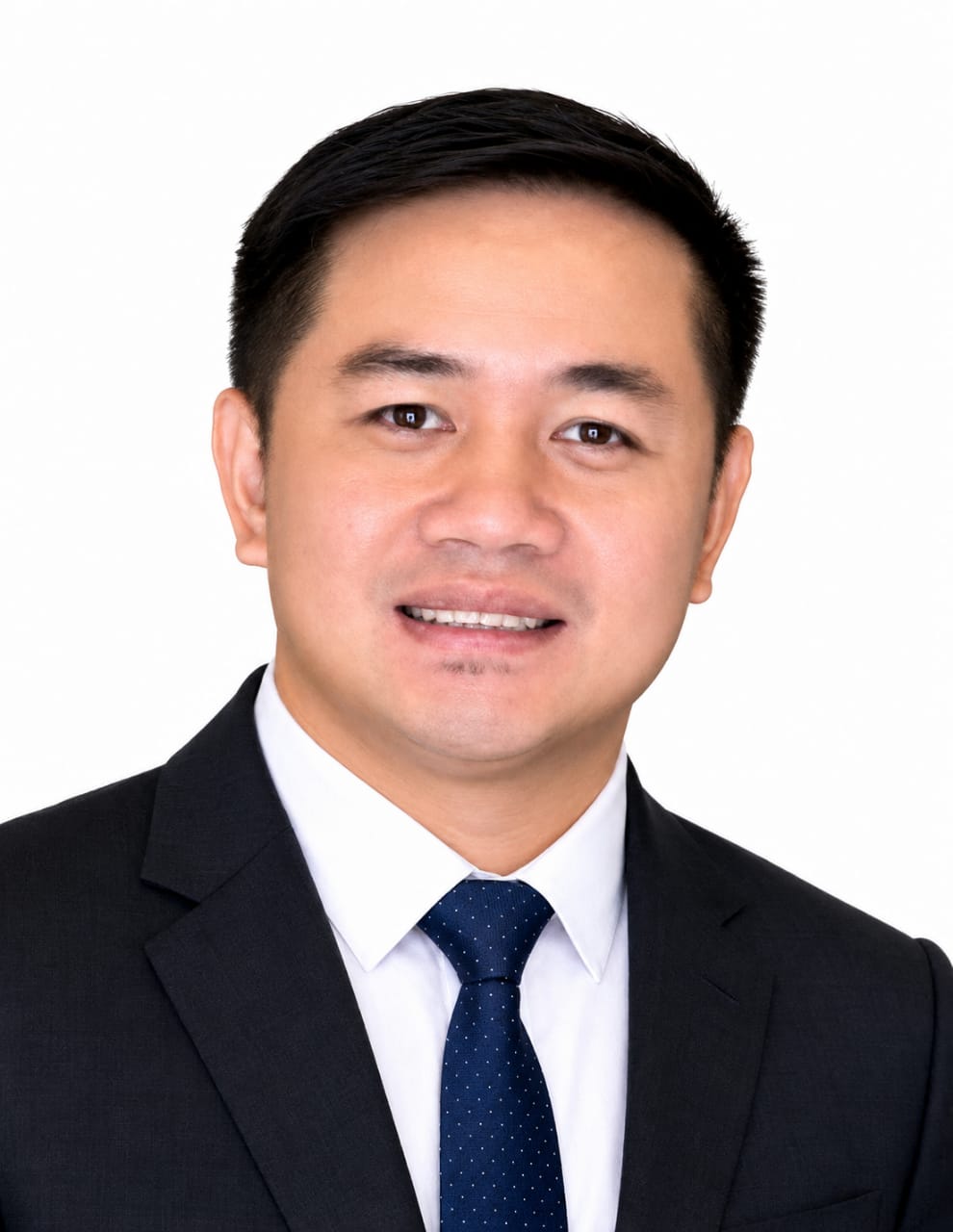 Portrait of an asian man in a dark suit, white shirt, and blue tie, smiling against a white background.