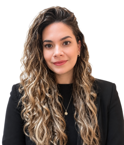 Ximena guzman - edited | enrizen | Head-and-shoulders portrait of a woman with long curly hair, wearing a black blazer and gold pendant necklace, smiling softly.