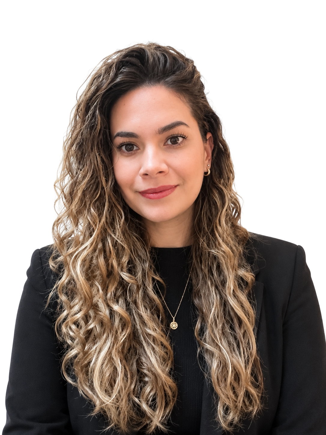 Head-and-shoulders portrait of a woman with long curly hair, wearing a black blazer and gold pendant necklace, smiling softly.
